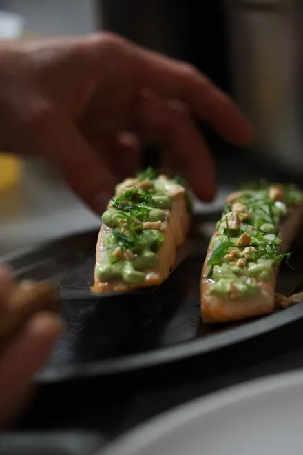 Truite nappée d'une sauce verte aux herbes, au moment du dressage en cuisine